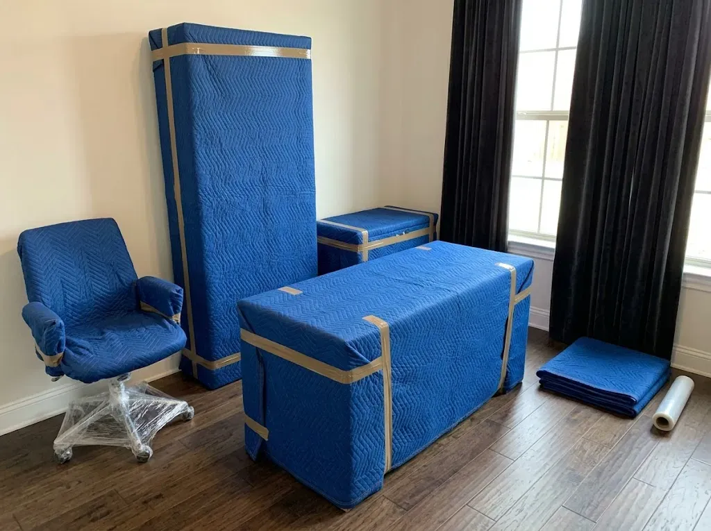 Moving crew applying furniture blankets and protective equipment in a home